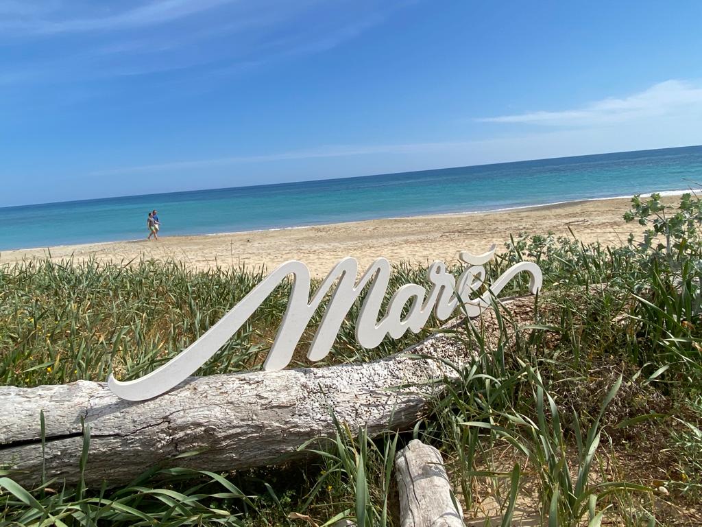 Logo lido marè in legno tra le dune del Salento